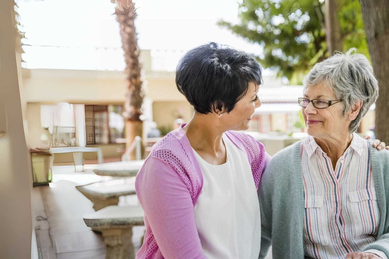 two women embracing on a bench